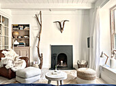 Living room with comfortable armchairs, shelves, decorative branches and antlers over a fireplace