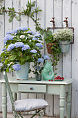 Hydrangea 'Endless Summer', wild strawberry and magic snow hung on the wall, bowl with sweet cherries and ceramic fish as water jug