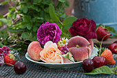 Duftende Rosenblüten, Pfirsiche, Nelke und Kamillenblüte als Tellerdekoration, Süßkirschen und Erdbeeren