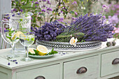 Lavender blossoms and rose blossom on tray, pitcher and glasses with water, mint and lemon as a refreshing drink