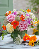 Sommerstrauß mit essbaren Blüten: Rosen, Kapuzinerkresse, Phlox, Giersch und wilde Möhre, Ringelblumenblüten liegen