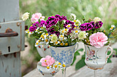 Unusual decoration idea with carnations, knautia, camomile and Queen Anne's Lace in cups on glass base
