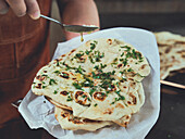 Naan bread being drizzled with olive oil