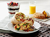 Egg and vegetable breakfast wrap sandwich with yogurt and fruit parfait with orange juice