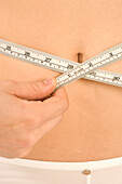 Young woman measuring her stomach