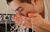 Young man washing his face