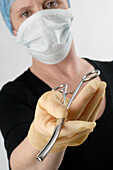 Masked doctor holding a pair of forceps