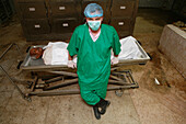 Pathologist stands over a corpse in a mortuary