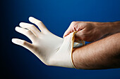 Man putting on a pair of protective latex gloves