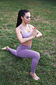 Young woman in purple sportswear doing yoga exercise