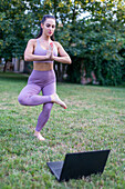 Young woman learning standing yoga pose from tutorial video