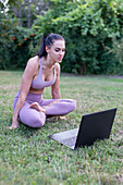 Young woman learning from tutorial video handstand lotus sit