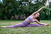 Young woman in sportswear stretching in split pose
