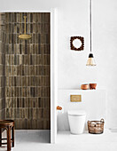 Shower area with brick tiles, adjacent toilet with pendant lamp