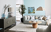 Light grey upholstered sofa with cushions, wooden coffee table and sideboard with fluted doors