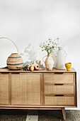 Vases on sideboard with wickerwork door