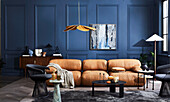 Light brown leather sofa, black chairs and coffee table in room with blue wall