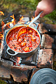 Cooking smoky sausage and black bean chilli on camp fire