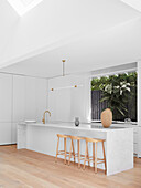 Elegant kitchen island with marble top and bar stools in white kitchen with window