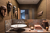 African masks and Brazilian slate in a cloakroom with walls covered in Foja grass