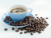 Tasse Kaffee mit Crema daneben Kaffeebohnen