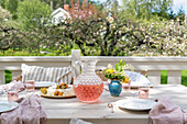 Gedeckter Tisch mit Kuchen und rosa Limonade auf der Terrasse