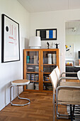 Classic chairs, glass-fronted cabinet and cantilever stool in dining room