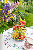 Pineapple, melon and grapes arranged on cake stand on garden table
