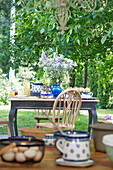 Tisch mit Eiern und Keramikkrügen im Garten