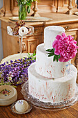 White, three tier cake decorated with a single peony
