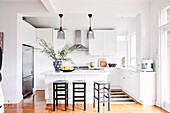 White fitted kitchen with breakfast bar and bar stools