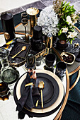 Gedeckter Tisch mit schwarzem Geschirr und goldfarbenem Besteck