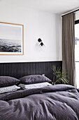 Double bed in bedroom with black painted wood panelling