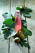 Fig liqueur surrounded by fresh figs and fig leaves
