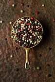 Rainbow peppercorns in a small metal container