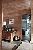 Wooden cabinet and fur boots in hallway with wooden panelling: view into bedroom with bunk beds