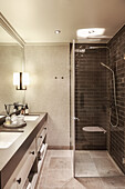 Washbasin with twin sinks and shower cubicle in illuminated bathroom