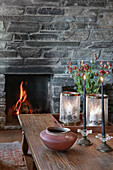 View over wooden coffee table to fire in stone fireplace in living room