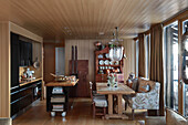 Black kitchen with mobile kitchen island and dining area with upholstered bench in a cabin