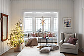 Weihnachtsbaum, hellgrauer Sessel und Sofa mit Kissen im Wohnzimmer
