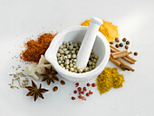 Different kinds of spices, in a mortar and spread around it