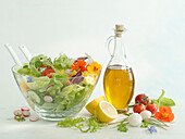 A bowl of garden salad, with a bottle of olive oil