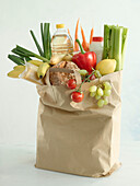 A brown paper shopping bag standing up with different types of food from the grocery store