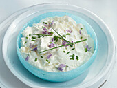 A bowl of curd cheese with chives and chive blossoms