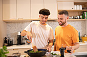 Gay male couple cooking in kitchen