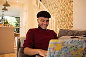 Happy young man using laptop on sofa