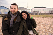 Happy couple in winter coats on beach