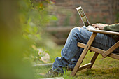 Man using laptop in lawn chair in garden