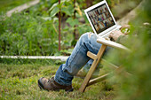 Man working on laptop in vegetable garden