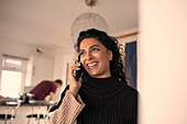 Happy woman talking on smart phone at home